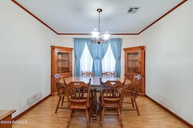 dining space with ornamental molding, an inviting chandelier, and light wood-type flooring