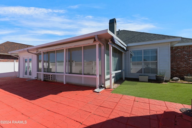 back of property featuring a yard, a patio, and a sunroom