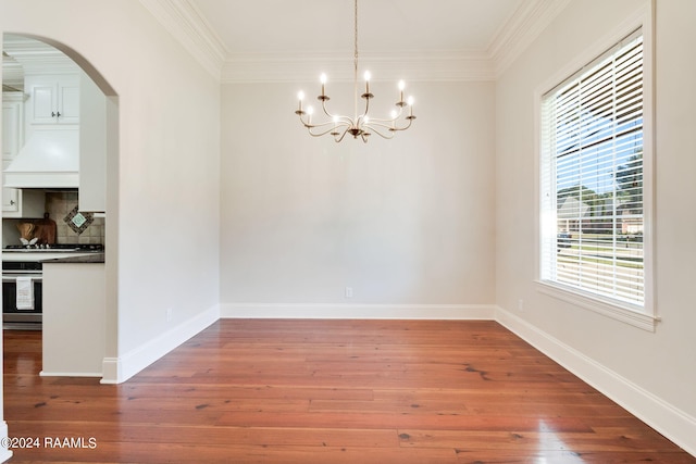 unfurnished dining area featuring ornamental molding, an inviting chandelier, and hardwood / wood-style floors