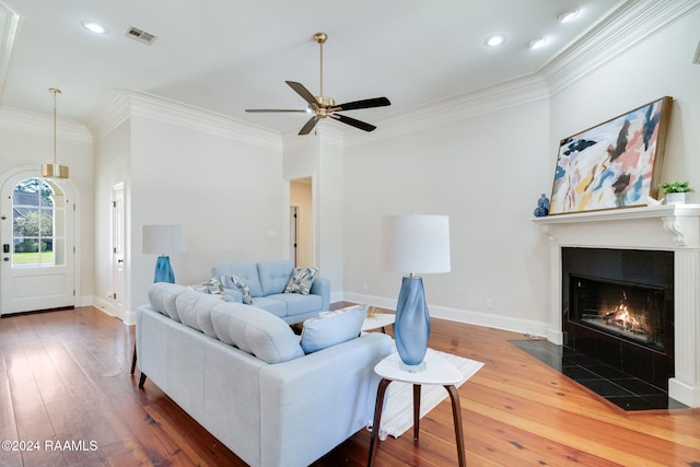 living room featuring ceiling fan, ornamental molding, a fireplace, and hardwood / wood-style floors