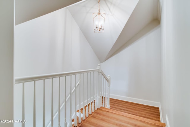 staircase with a notable chandelier and hardwood / wood-style flooring