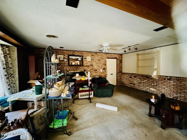 miscellaneous room with a textured ceiling, brick wall, and ceiling fan