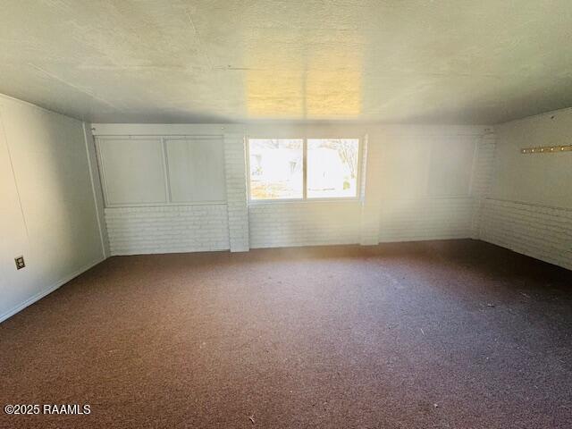 spare room featuring brick wall and carpet