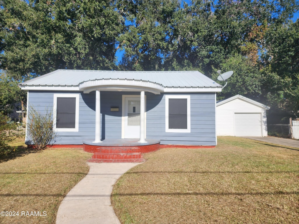 bungalow with a porch, a front lawn, an outbuilding, and a garage