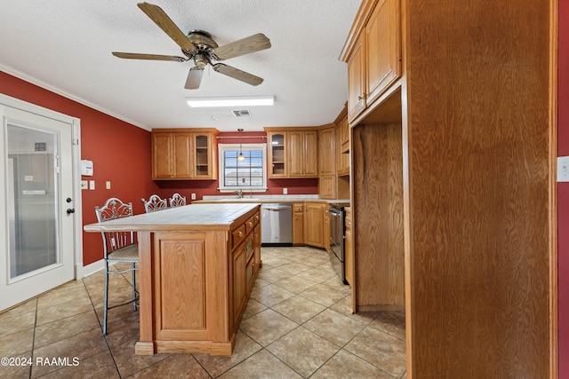 kitchen with ceiling fan, ornamental molding, stainless steel appliances, tile counters, and a center island