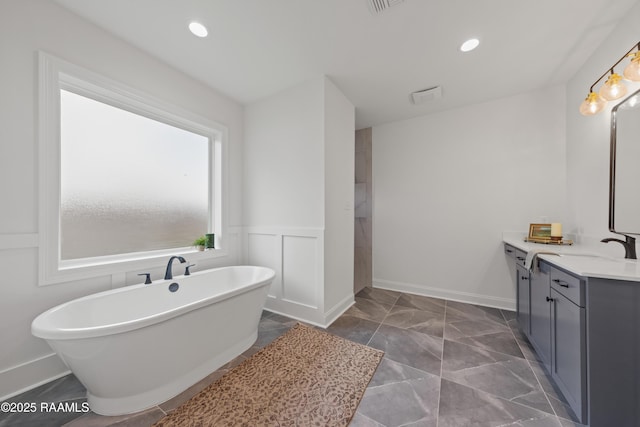 full bath featuring a wainscoted wall, a freestanding bath, recessed lighting, marble finish floor, and vanity