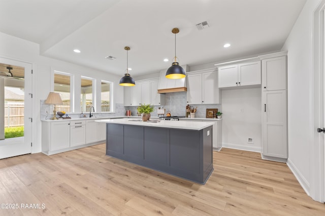 kitchen featuring decorative backsplash, light countertops, visible vents, and white cabinetry