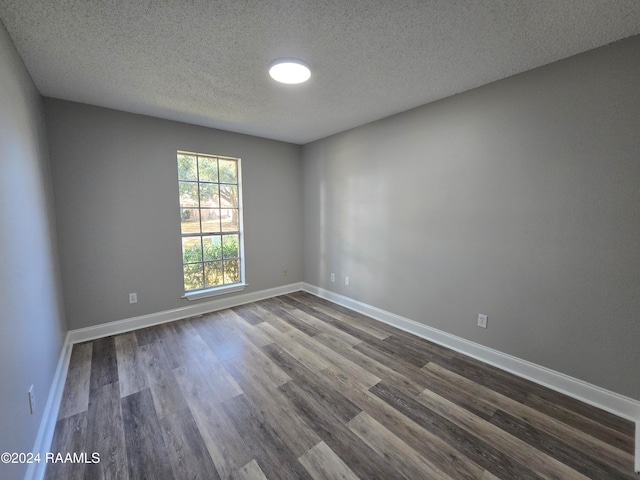 empty room featuring a textured ceiling and dark hardwood / wood-style floors