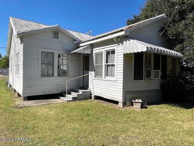 bungalow-style house with cooling unit and a front lawn