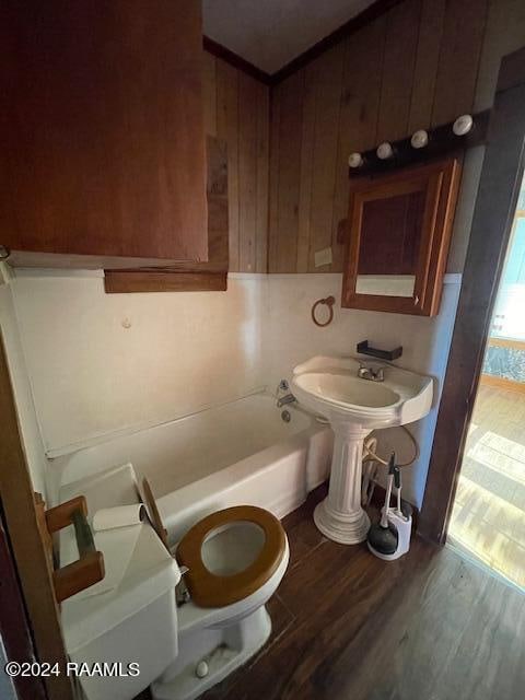 bathroom featuring toilet, a tub, and wood-type flooring