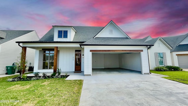 view of front facade featuring covered porch, a garage, and a lawn