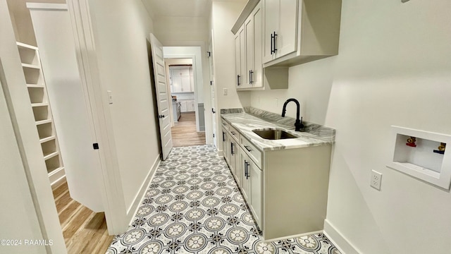 kitchen with light stone countertops, light hardwood / wood-style floors, and sink