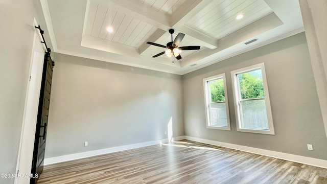 spare room with beamed ceiling, ceiling fan, a barn door, and light hardwood / wood-style flooring