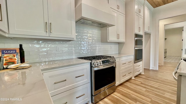 kitchen with white cabinets, stainless steel appliances, light hardwood / wood-style flooring, and range hood