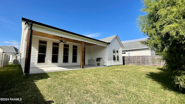 rear view of property featuring a yard, central AC, and ceiling fan