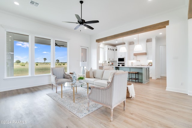 living room with ceiling fan, sink, light hardwood / wood-style floors, and ornamental molding