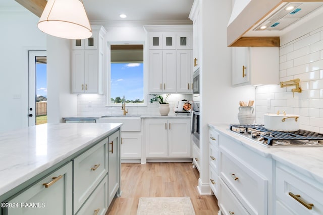 kitchen featuring backsplash, crown molding, white cabinets, and extractor fan