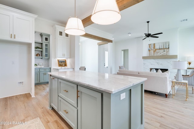 kitchen with light stone counters, pendant lighting, light hardwood / wood-style floors, decorative backsplash, and a kitchen island