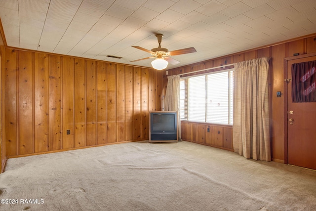 empty room with light carpet, ceiling fan, and wood walls