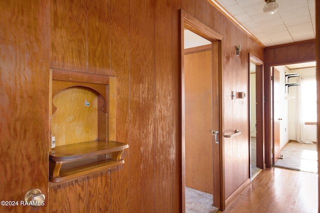 hallway with light hardwood / wood-style floors and wooden walls