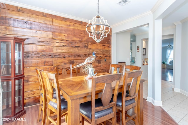 dining space featuring ornamental molding, wooden walls, ceiling fan with notable chandelier, and hardwood / wood-style floors