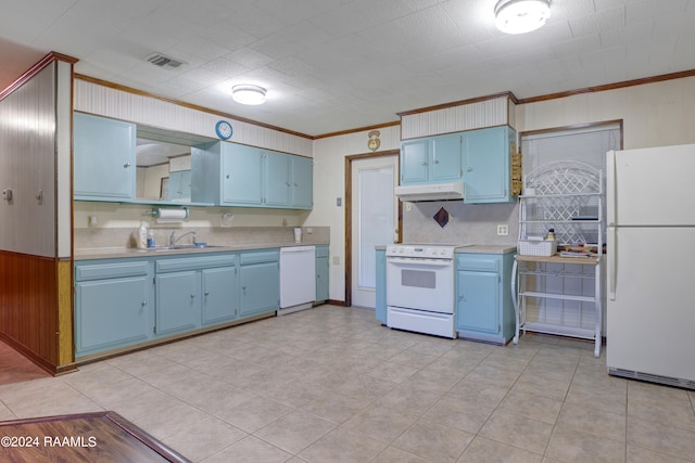 kitchen with wooden walls, ornamental molding, sink, light tile patterned floors, and white appliances