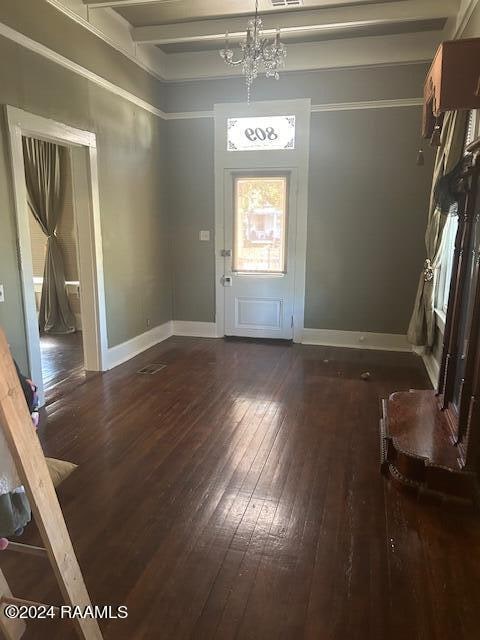 entrance foyer featuring beam ceiling, dark hardwood / wood-style floors, and an inviting chandelier