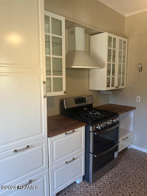 kitchen featuring crown molding, gas stove, wall chimney exhaust hood, and white cabinets