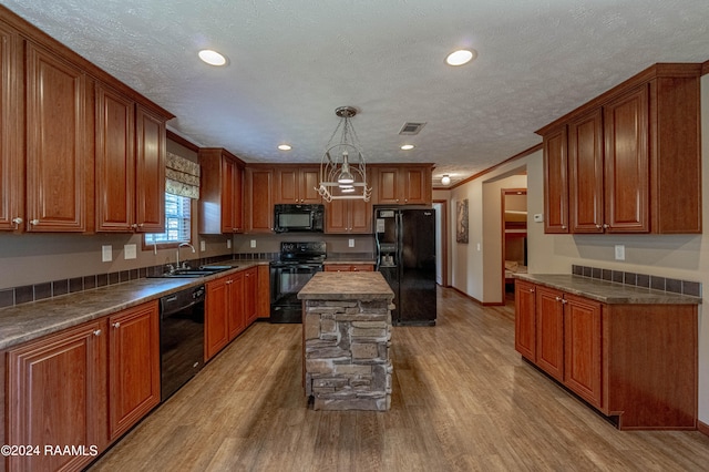 kitchen featuring sink, black appliances, a center island, and light wood-type flooring