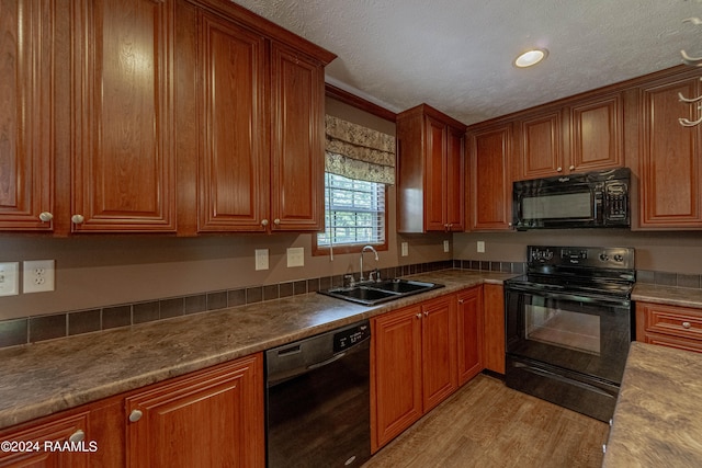 kitchen with sink, black appliances, light stone countertops, and light hardwood / wood-style floors