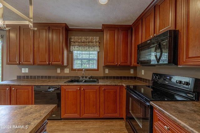 kitchen featuring a textured ceiling, ornamental molding, black appliances, light hardwood / wood-style floors, and sink