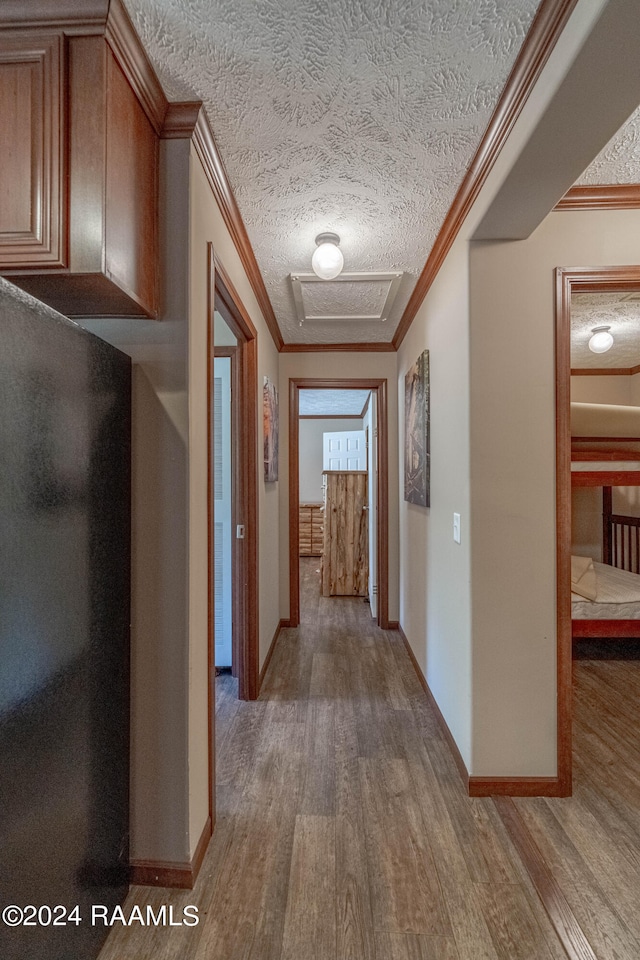 corridor with crown molding, hardwood / wood-style flooring, and a textured ceiling