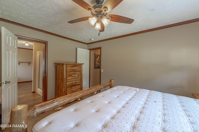 bedroom with crown molding, wood-type flooring, a textured ceiling, and ceiling fan