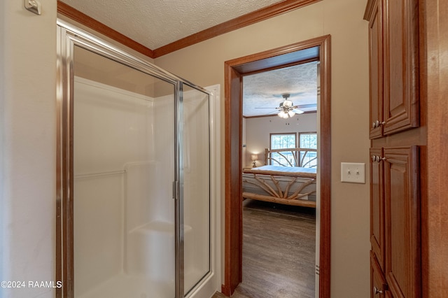 bathroom featuring hardwood / wood-style flooring, ornamental molding, an enclosed shower, a textured ceiling, and ceiling fan