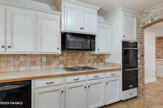 kitchen featuring decorative backsplash, white cabinets, light tile patterned floors, black appliances, and tile counters