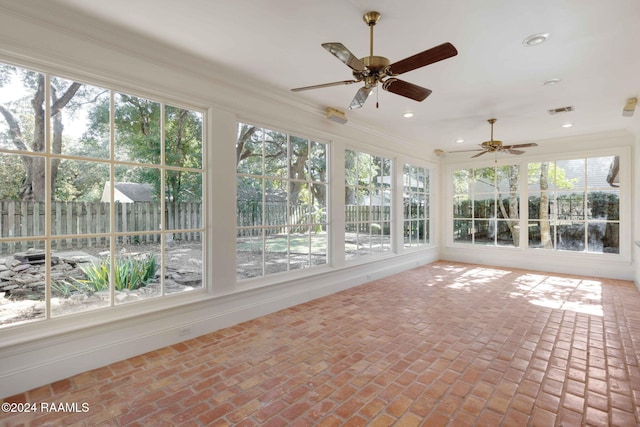 unfurnished sunroom featuring ceiling fan and a wealth of natural light