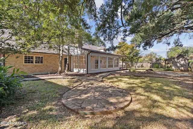 back of property with a patio, a sunroom, a lawn, and a storage shed