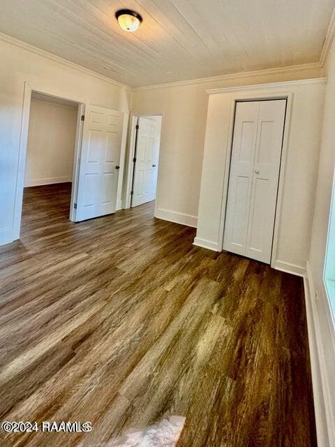 unfurnished bedroom featuring a closet, ornamental molding, dark hardwood / wood-style flooring, and wooden ceiling