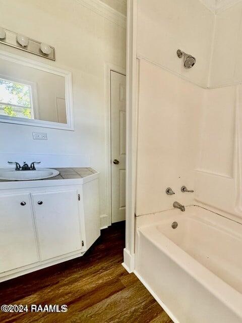 bathroom featuring vanity, shower / bath combination, crown molding, and wood-type flooring