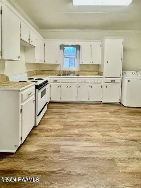 kitchen featuring sink, separate washer and dryer, white electric range oven, white cabinets, and light hardwood / wood-style floors