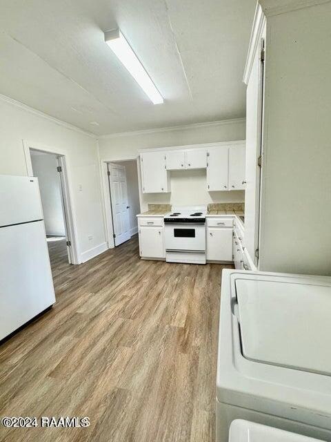 kitchen featuring washer / dryer, light hardwood / wood-style flooring, ornamental molding, white cabinetry, and white appliances