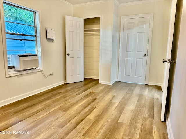 unfurnished bedroom featuring crown molding, light hardwood / wood-style flooring, cooling unit, and a closet