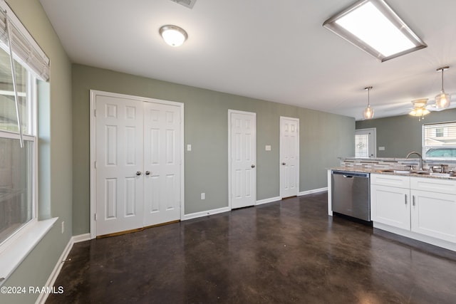 kitchen with white cabinetry, sink, stainless steel dishwasher, hanging light fixtures, and decorative backsplash