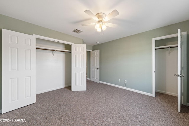 unfurnished bedroom with carpet, multiple closets, and ceiling fan