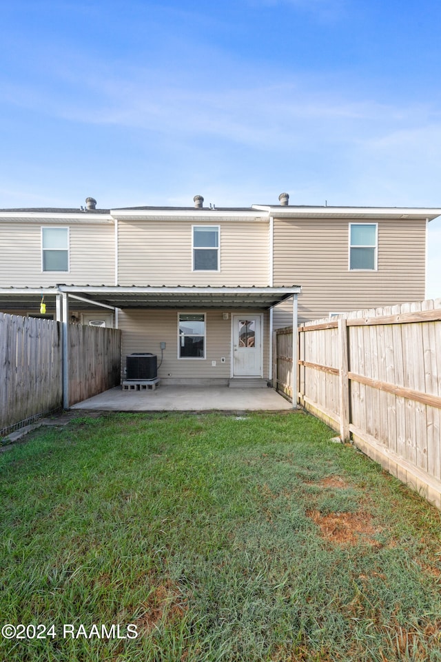 rear view of house with cooling unit, a yard, and a patio area