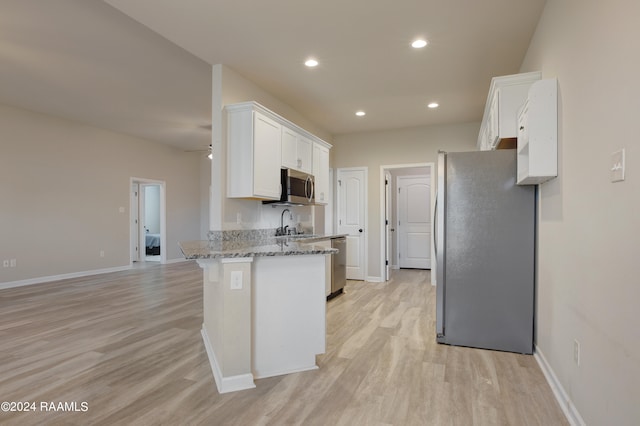 kitchen featuring light hardwood / wood-style floors, white cabinets, light stone countertops, and stainless steel appliances