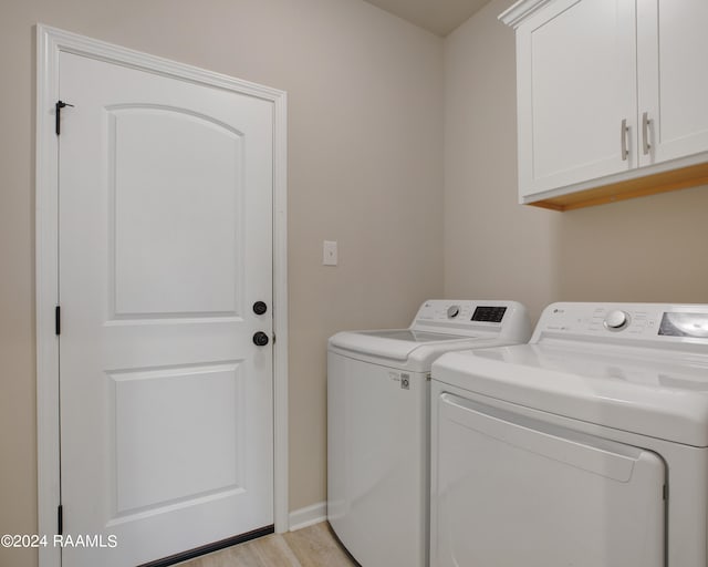 clothes washing area featuring cabinets, separate washer and dryer, and light hardwood / wood-style floors