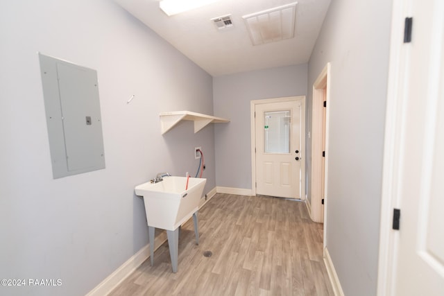 laundry room with electric panel and light hardwood / wood-style floors