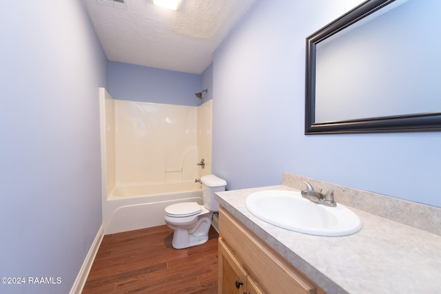 full bathroom with wood-type flooring, bathing tub / shower combination, a textured ceiling, toilet, and vanity