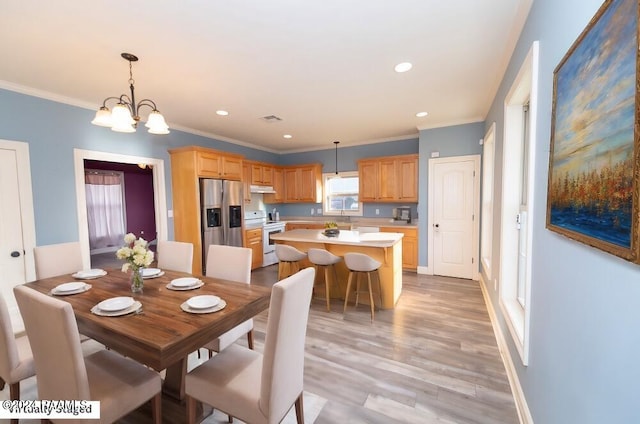 dining space featuring sink, a notable chandelier, ornamental molding, and light hardwood / wood-style flooring